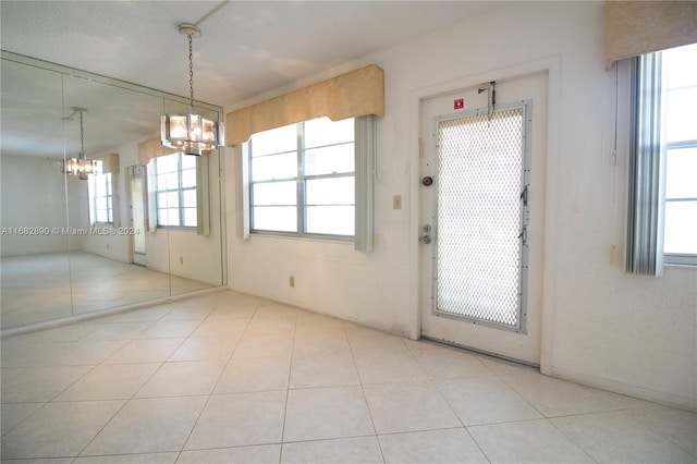 interior space with a chandelier, light tile patterned floors, and a healthy amount of sunlight