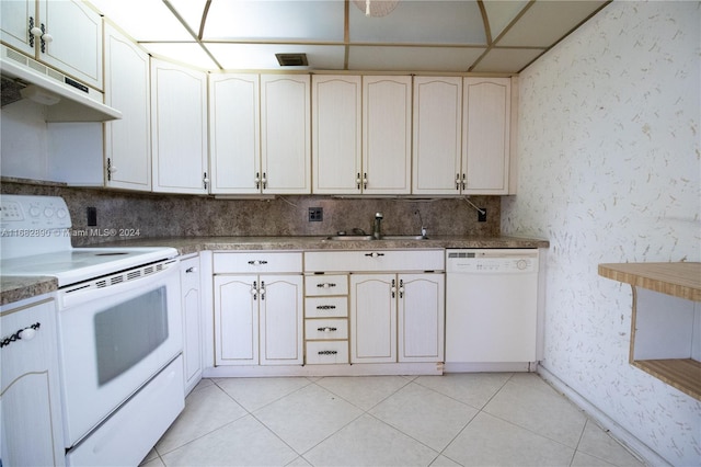 kitchen featuring a paneled ceiling, white appliances, sink, and light tile patterned floors