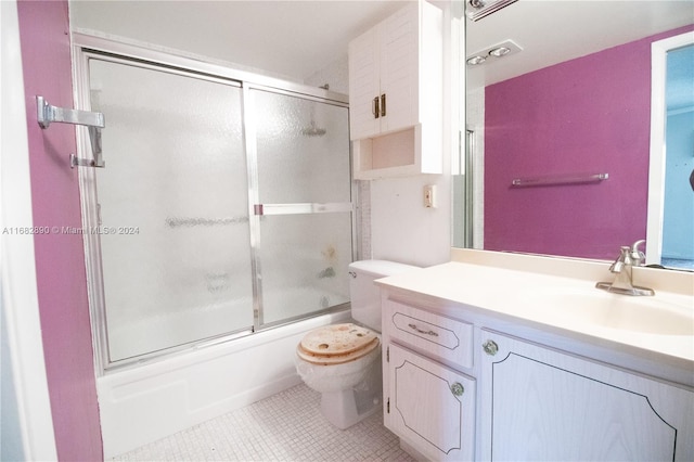 full bathroom with tile patterned flooring, vanity, bath / shower combo with glass door, and toilet