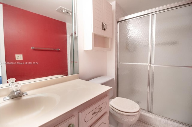 bathroom with tile patterned floors, vanity, toilet, and a shower with shower door