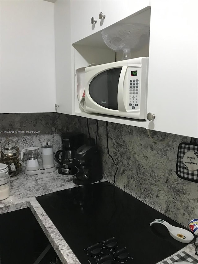 details with black electric stovetop, white cabinetry, and tasteful backsplash