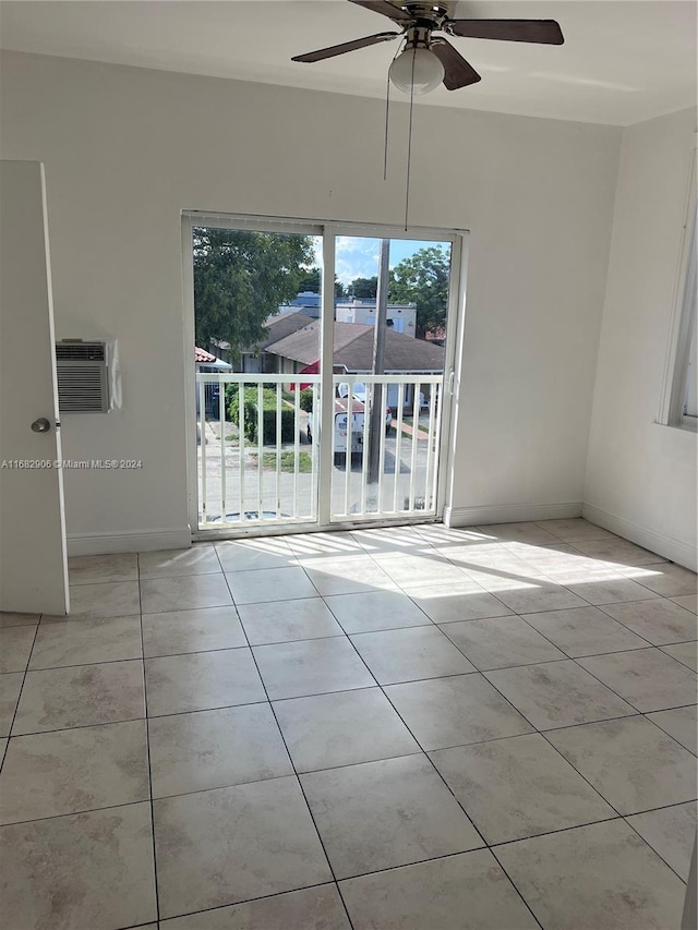 tiled empty room with a wall unit AC and ceiling fan