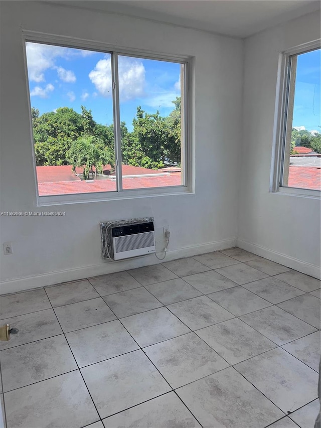 unfurnished room with an AC wall unit and light tile patterned floors