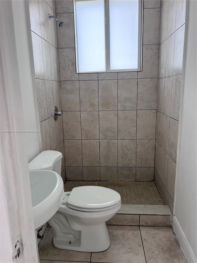 bathroom with tile patterned floors, sink, a tile shower, and toilet