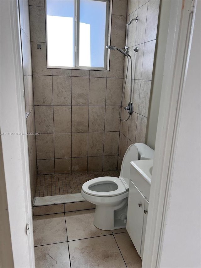 bathroom with vanity, tiled shower, toilet, and tile patterned flooring