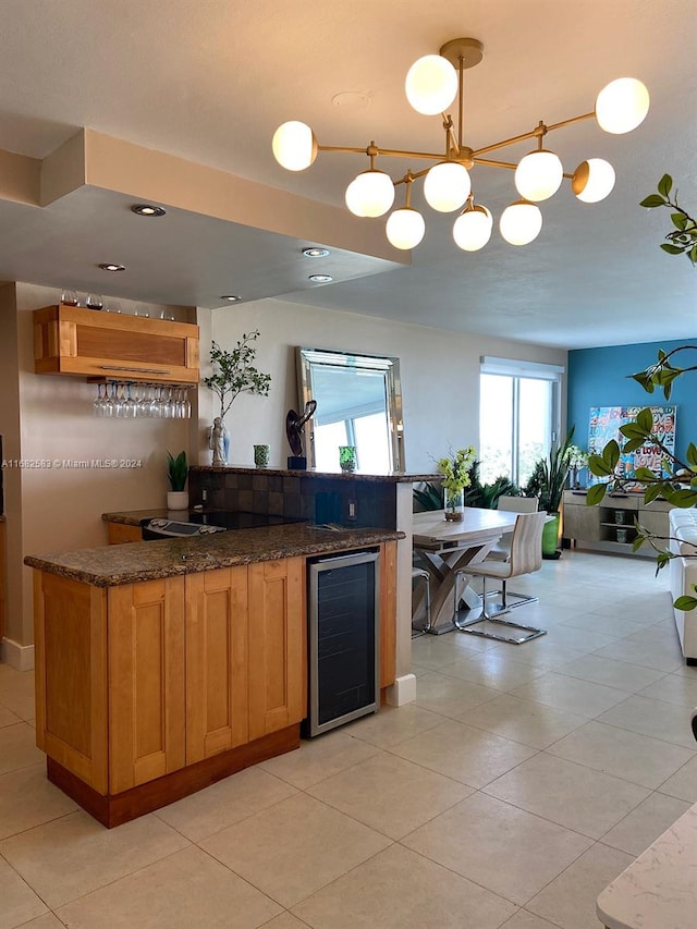 kitchen with wine cooler, dark stone countertops, hanging light fixtures, and light tile patterned floors