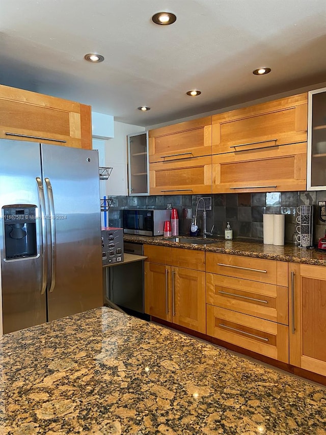 kitchen with tasteful backsplash, stainless steel appliances, sink, and dark stone counters