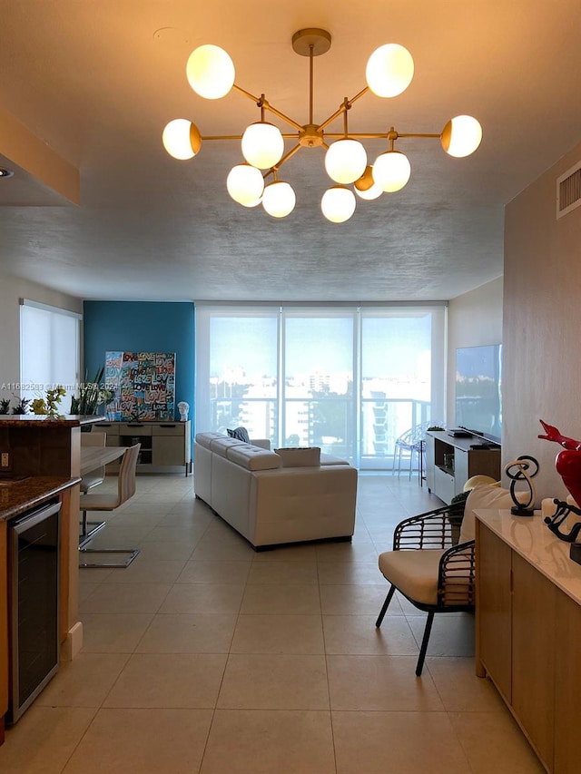 living room with an inviting chandelier, a textured ceiling, light tile patterned floors, and beverage cooler