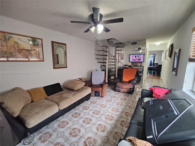 living room featuring ceiling fan and a textured ceiling