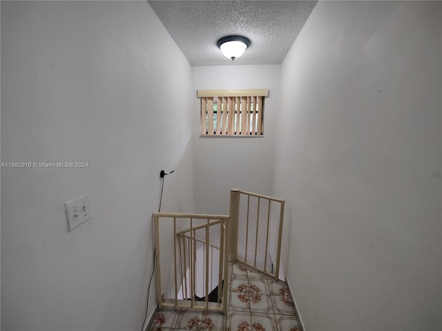 stairway featuring a textured ceiling