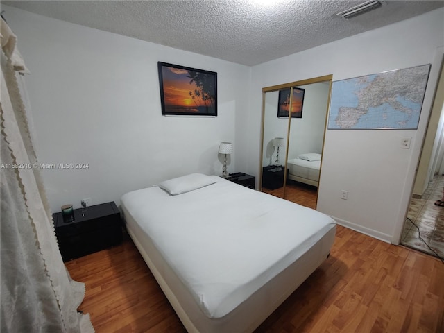 bedroom featuring a closet, a textured ceiling, and hardwood / wood-style flooring