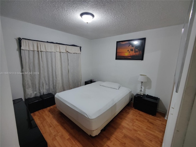 bedroom featuring a textured ceiling and hardwood / wood-style flooring