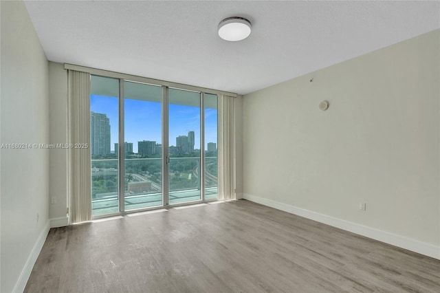 unfurnished room with expansive windows, a textured ceiling, and hardwood / wood-style flooring