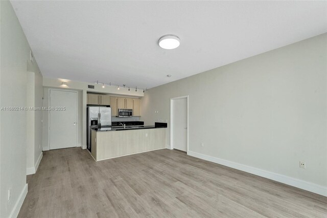 kitchen with appliances with stainless steel finishes, light brown cabinets, kitchen peninsula, and light hardwood / wood-style flooring