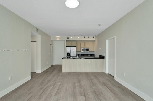 kitchen with light wood-type flooring, light brown cabinets, kitchen peninsula, stainless steel appliances, and backsplash