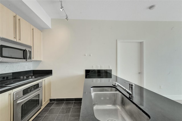 kitchen featuring stainless steel appliances, rail lighting, dark tile patterned flooring, and sink