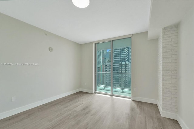 empty room with a wall of windows and light wood-type flooring