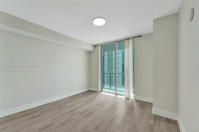 unfurnished room with a wall of windows, light wood-type flooring, and a wealth of natural light