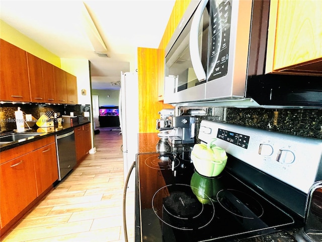 kitchen with decorative backsplash, sink, stainless steel appliances, and light wood-type flooring