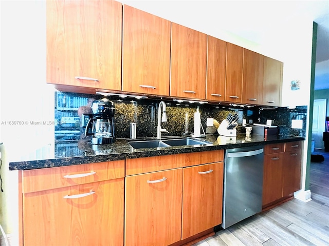 kitchen featuring sink, stainless steel dishwasher, decorative backsplash, dark stone countertops, and light hardwood / wood-style floors