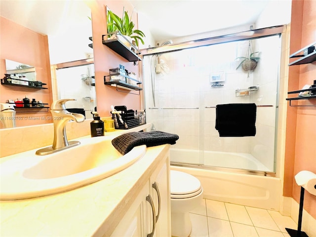 full bathroom featuring toilet, vanity, tile patterned floors, and enclosed tub / shower combo