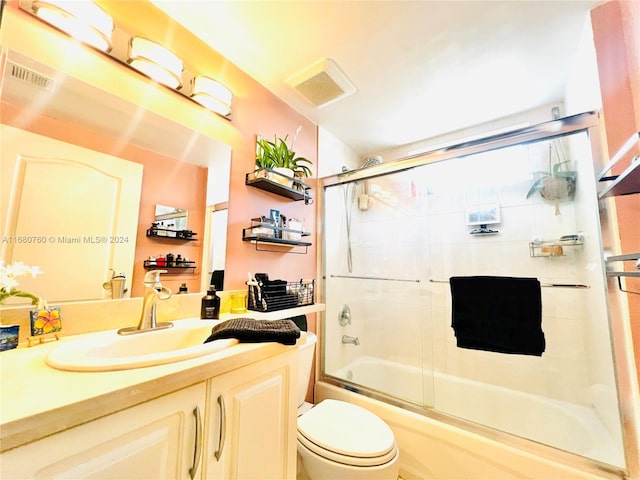 full bathroom featuring toilet, vanity, and combined bath / shower with glass door