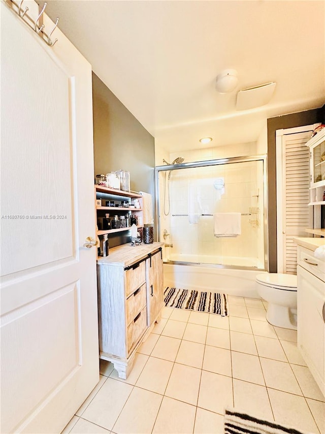 full bathroom featuring tile patterned flooring, vanity, toilet, and bath / shower combo with glass door