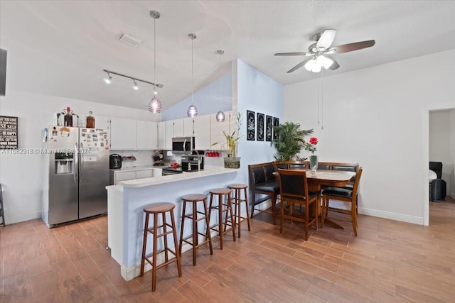 kitchen with white cabinetry, stainless steel appliances, decorative light fixtures, and light wood-type flooring