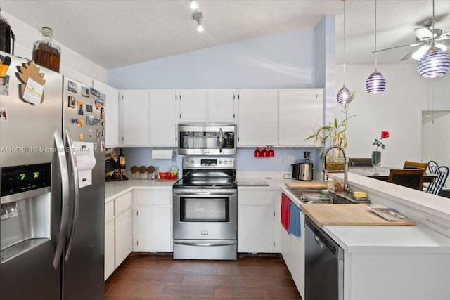 kitchen featuring appliances with stainless steel finishes, sink, vaulted ceiling, white cabinets, and dark hardwood / wood-style floors