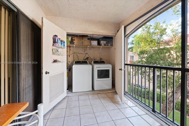 laundry room featuring washer and clothes dryer, light tile patterned floors, and plenty of natural light