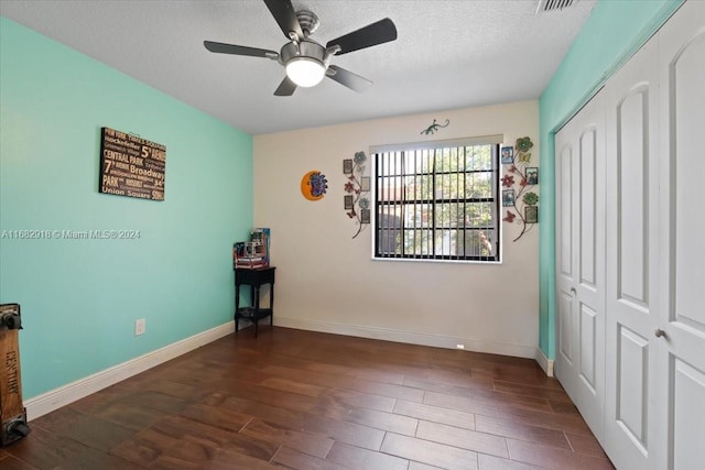 unfurnished bedroom with a textured ceiling, dark hardwood / wood-style floors, a closet, and ceiling fan