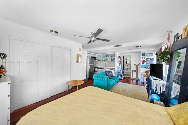 bedroom featuring a closet, ceiling fan, dark wood-type flooring, and stainless steel refrigerator