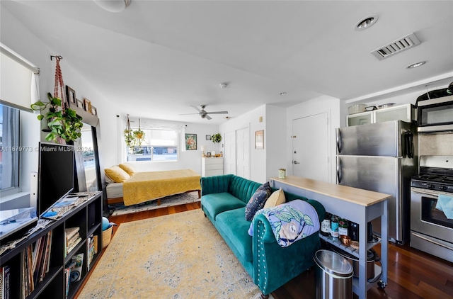 bedroom with stainless steel fridge, ceiling fan, and dark hardwood / wood-style floors