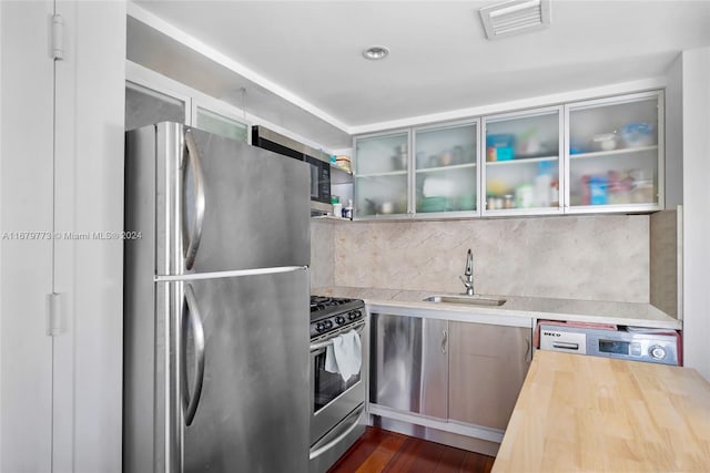 kitchen with butcher block counters, stainless steel appliances, sink, and dark hardwood / wood-style flooring