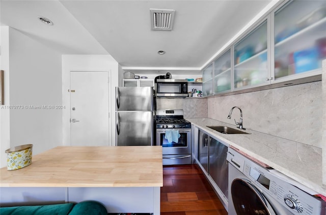 kitchen featuring washer / dryer, sink, dark hardwood / wood-style flooring, stainless steel appliances, and wooden counters