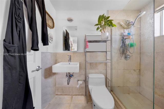 bathroom featuring tile patterned floors, toilet, sink, tile walls, and walk in shower