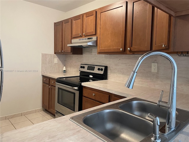 kitchen with light tile patterned flooring, stainless steel electric stove, decorative backsplash, and sink