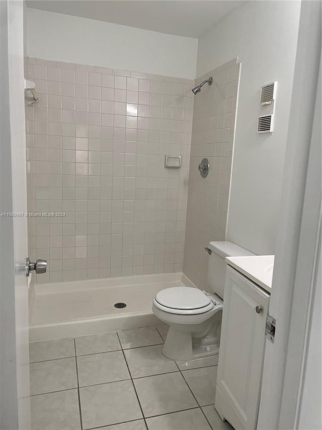 bathroom featuring vanity, toilet, tiled shower, and tile patterned flooring