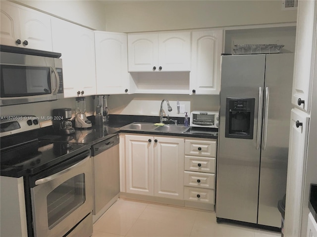 5161 Collins Ave Unit 801, Miami Beach, FL 33140 - kitchen featuring stainless steel appliances, dark countertops, light tile patterned flooring, and white cabinetry