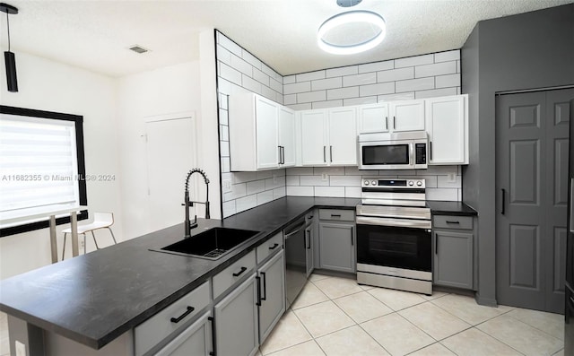 kitchen with gray cabinetry, stainless steel appliances, white cabinetry, and sink