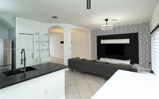 living room featuring light tile patterned floors, a notable chandelier, a textured ceiling, and sink