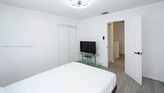 bedroom with a closet, a textured ceiling, and light hardwood / wood-style floors