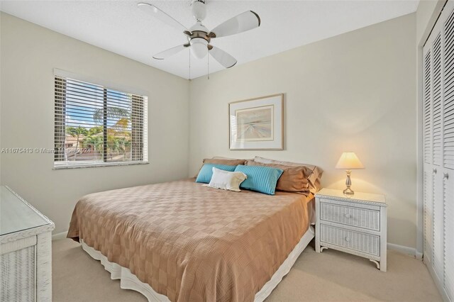 bedroom featuring light carpet, a closet, and ceiling fan