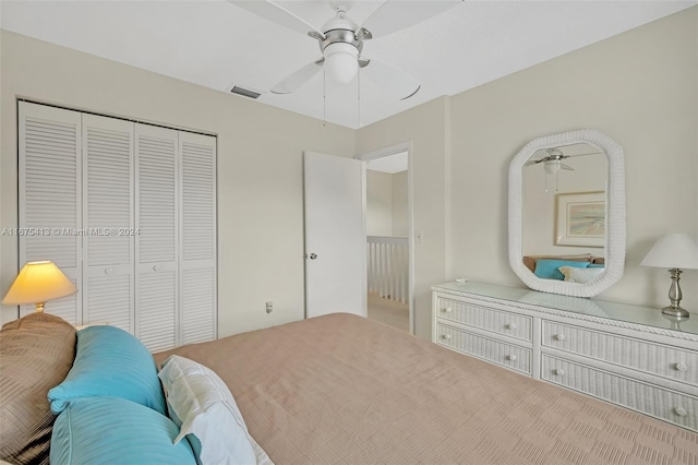 carpeted bedroom with ceiling fan and a closet