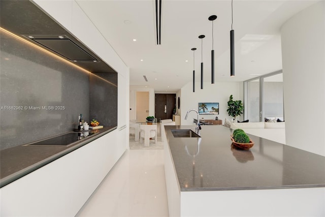 kitchen with dark stone counters, expansive windows, sink, hanging light fixtures, and white cabinetry