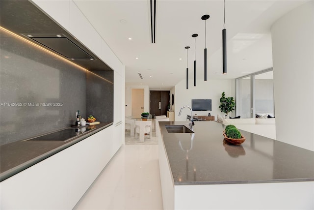 kitchen with pendant lighting, white cabinets, black electric stovetop, sink, and dark stone countertops