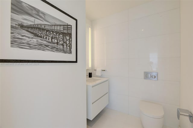 bathroom featuring vanity, tile walls, and toilet