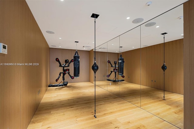 workout room with wood walls and light hardwood / wood-style floors