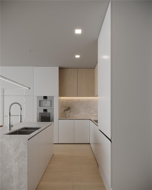 kitchen with light brown cabinetry, sink, light hardwood / wood-style flooring, and decorative backsplash