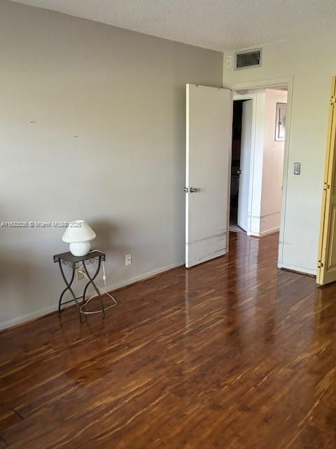 spare room with dark hardwood / wood-style flooring and a textured ceiling